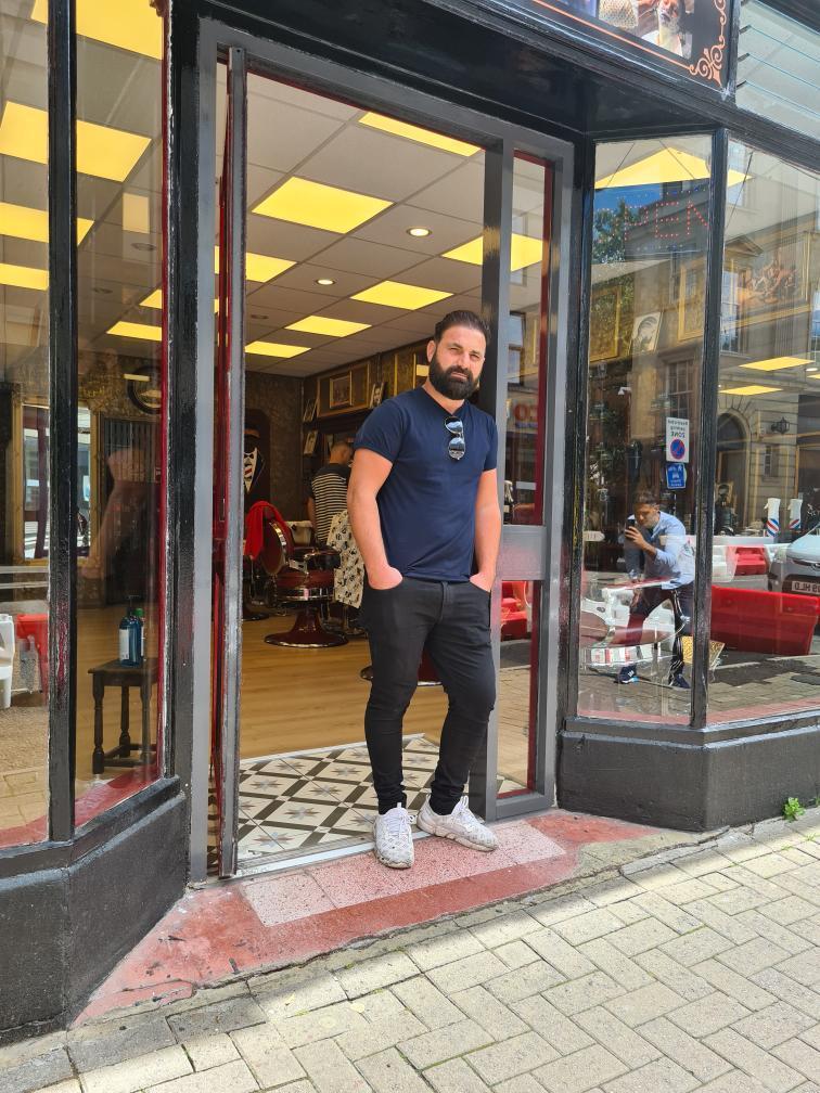 A barber on the doorstep of Boss Barbers at 30 Westgate Buildings, Bath.